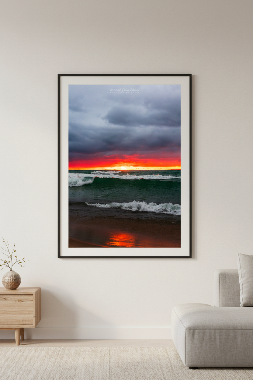 Large fine art portrait print of moody fiery red orange sunset with storm clouds and churning teal waves on Lake Michigan beach Leland Michigan September 2024 displayed in modern living room