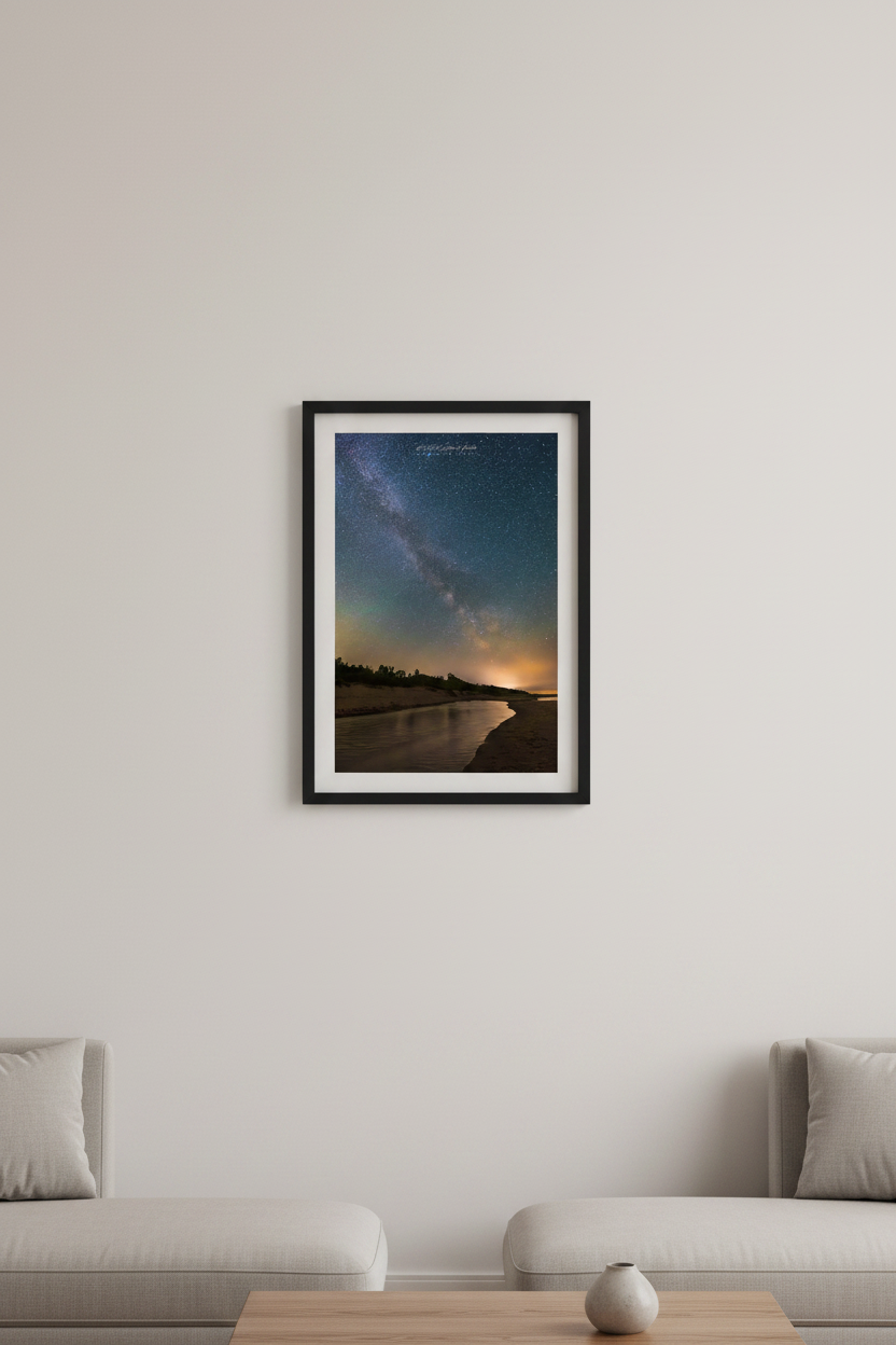 Small fine art portrait print of the Milky Way arching above a winding tidal creek through sandy dunes with silhouetted tree line and warm orange horizon glow at Otter Creek Michigan June 17 2023 displayed in modern living room