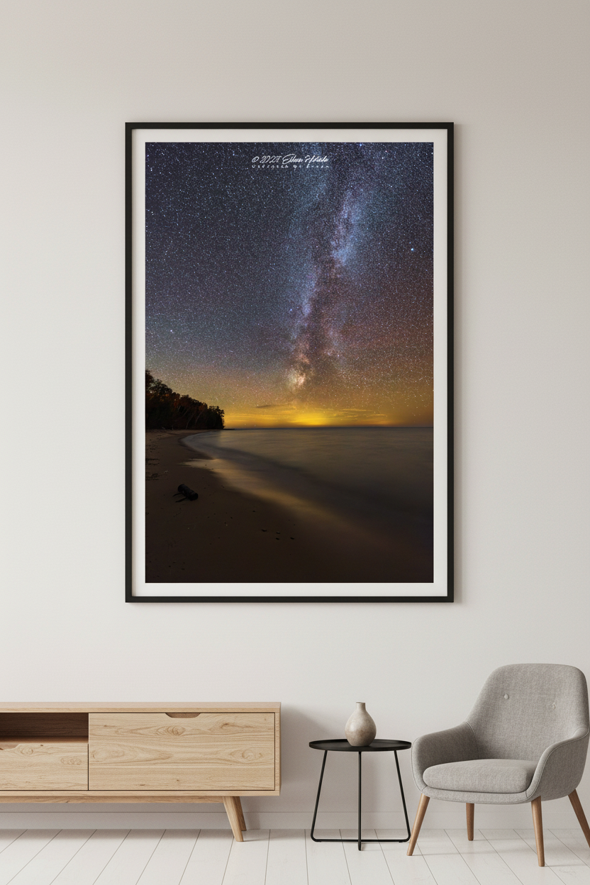Large fine art portrait print of the Milky Way rising over Lake Michigan from Christmas Cove Beach Northport Michigan October 22 2022 at 10:08pm with warm golden horizon glow and sandy beach foreground displayed in modern living room