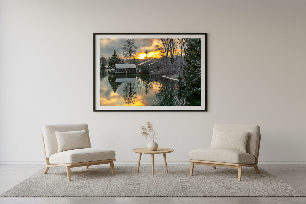 Large fine art landscape print of snowy Christmas boathouse scene with fiery golden sunrise reflecting in still water Leland Michigan December 2022 displayed in modern living room