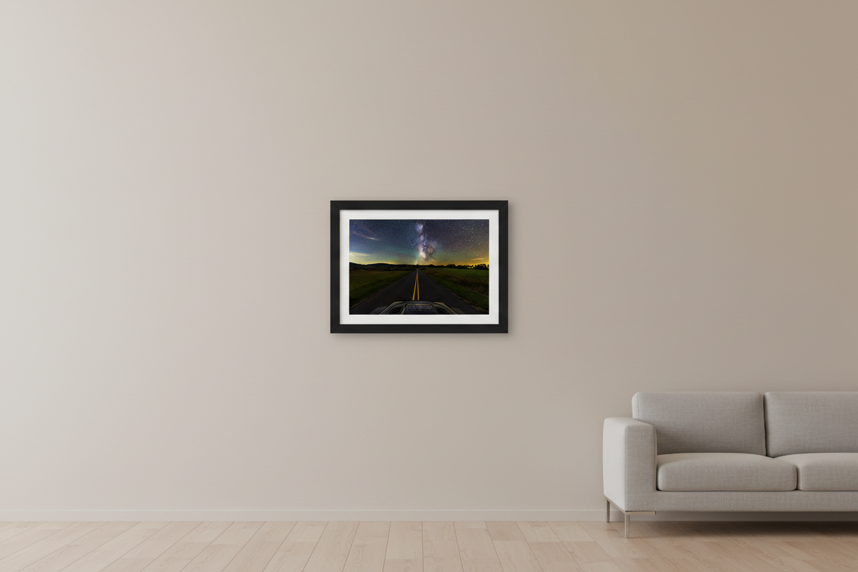 Small fine art landscape print of the Milky Way galactic core rising over a rural two-lane road viewed from vehicle hood POV with open fields and rolling hills near Sleeping Bear Dunes Michigan September 4 2024 at 10:50pm displayed in modern living room