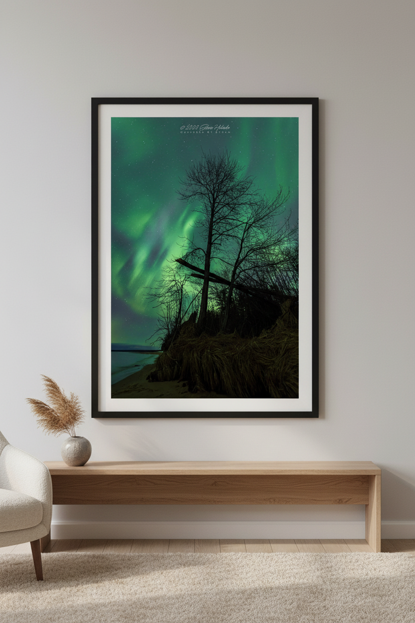 Large fine art portrait print of vivid green Northern Lights behind silhouetted bare tree and weathered wooden cross on eroding Lake Superior bluff Michigan Upper Peninsula April 23 2023 displayed in modern living room