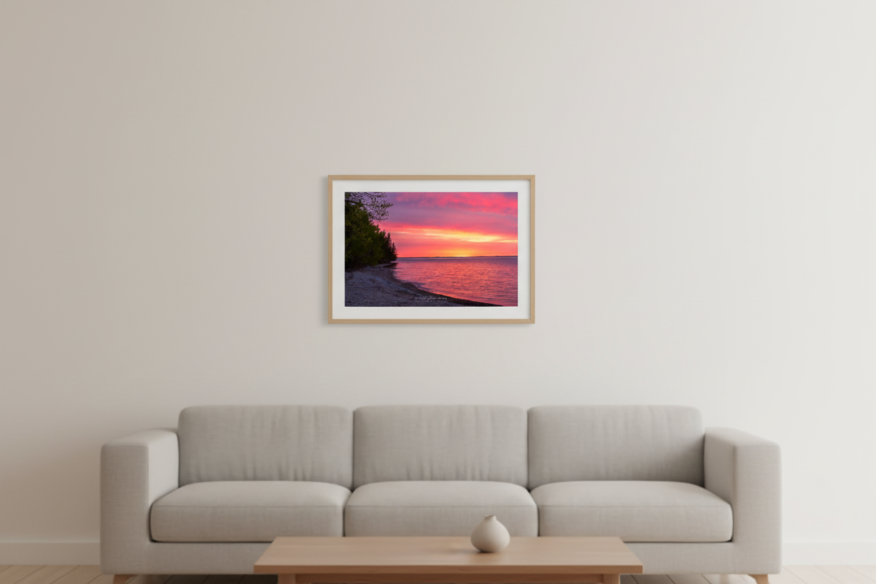 Small fine art landscape print of vivid magenta and orange Mother's Day sunrise over Grand Traverse Bay forested shoreline Michigan May 2023 displayed in modern living room