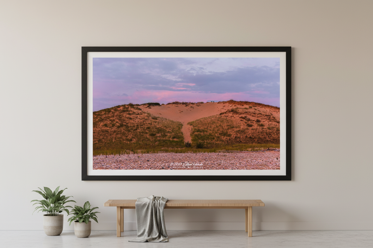 Large fine art print of warm terracotta sand dune face with rocky pebble beach foreground and soft lavender purple sky at Sleeping Bear Point MI displayed in modern living room