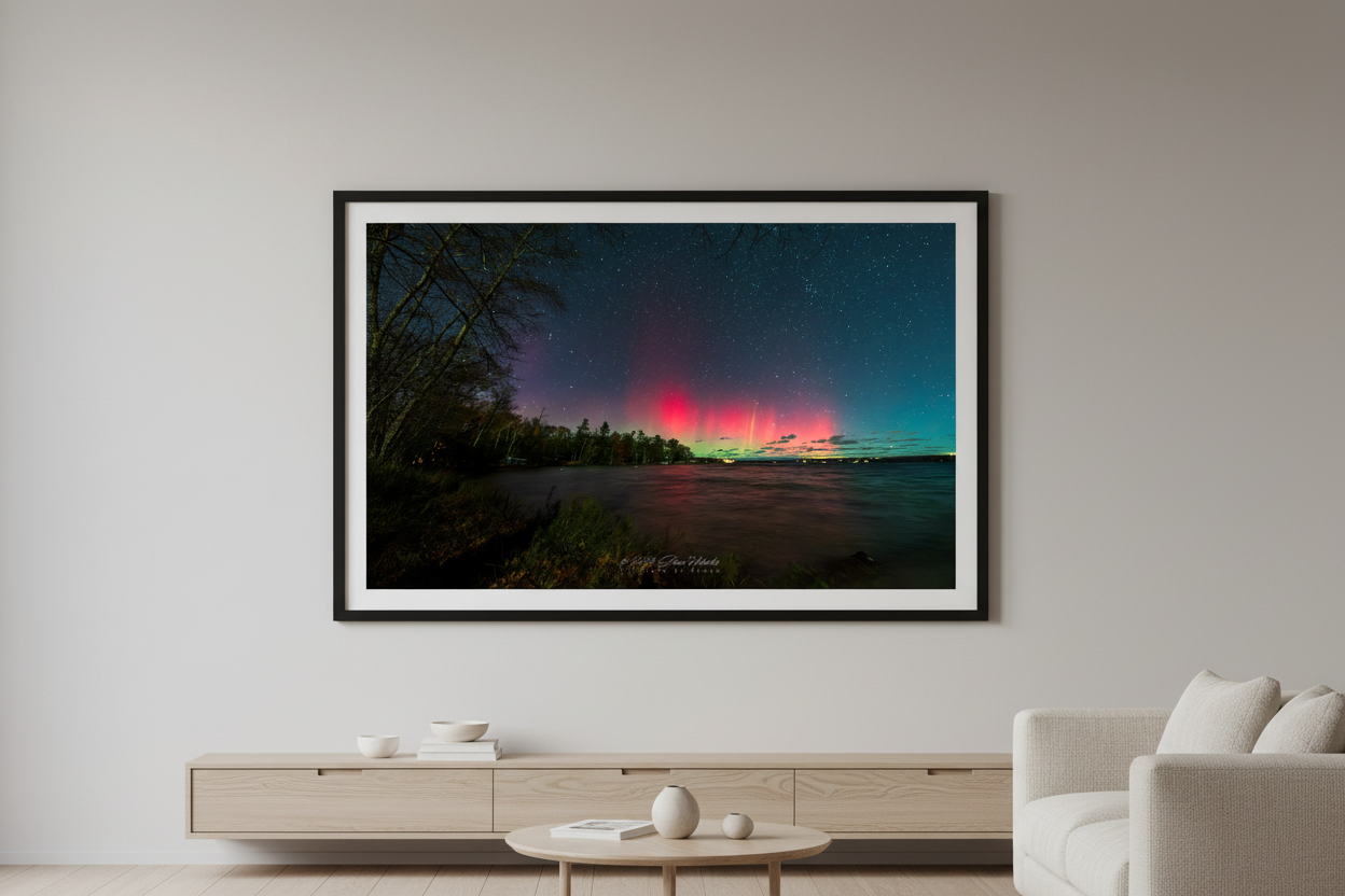 Large fine art print of vivid crimson red aurora pillars with yellow-green spike rising over Lake Leelanau wooded shoreline from Leland Michigan November 8 2024 8:33pm displayed in modern living room