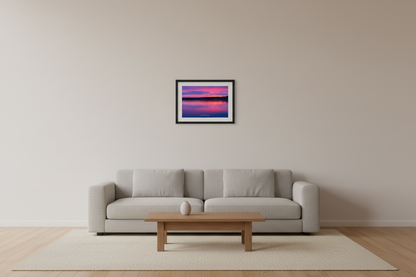 Small fine art long exposure landscape print of stunning magenta violet sunrise with mirrored pink purple layers reflecting across glassy Lake Leelanau Leland Michigan April 2022 displayed in modern living room