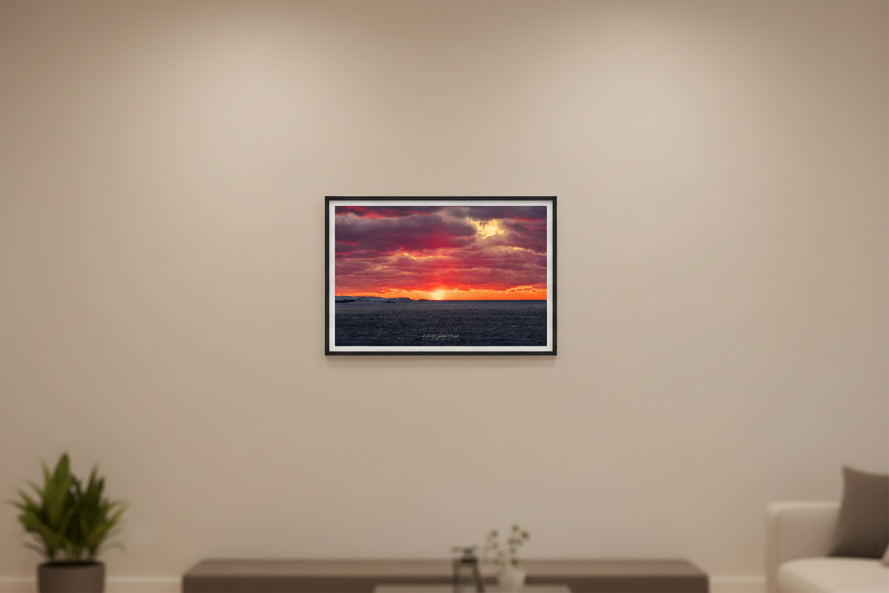 Small fine art landscape print of fiery crimson and purple sunset color explosion over snow-covered Sleeping Bear Point with dark choppy Lake Michigan water January 2023 displayed in modern living room