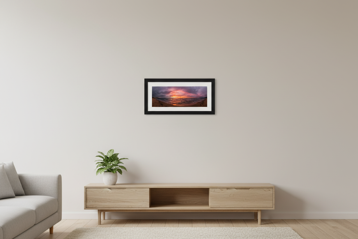 Small fine art 3:1 panoramic print of stormy sunset over Good Harbor Beach with fiery orange pink and purple sky over choppy Lake Michigan waters displayed in modern living room