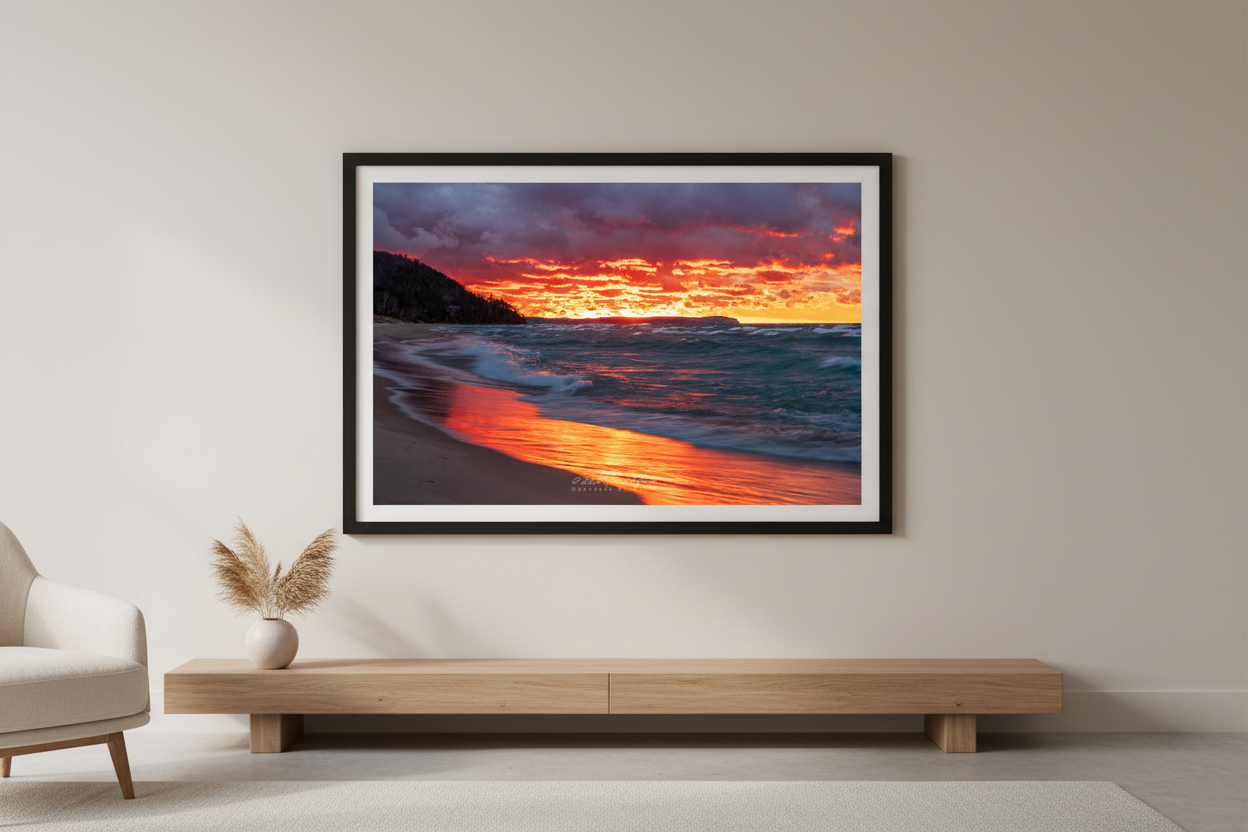 Large fine art landscape print of blazing crimson and orange November fire sunset with glowing ember-like clouds fiery reflection across wet sandy beach turquoise-teal churning waves dark forested bluff and distant Sleeping Bear Dunes headland at Leland Lake Michigan November 30 2021 displayed in modern living room