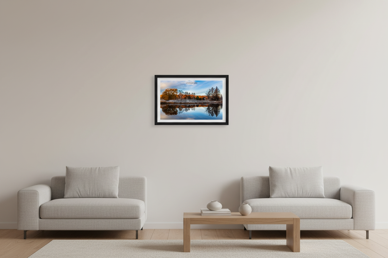 Small fine art print of hoarfrost covered shoreline with warm orange fall foliage and perfect mirror reflection on a still pond in Veronica Valley Michigan November 20 2023 displayed in modern living room