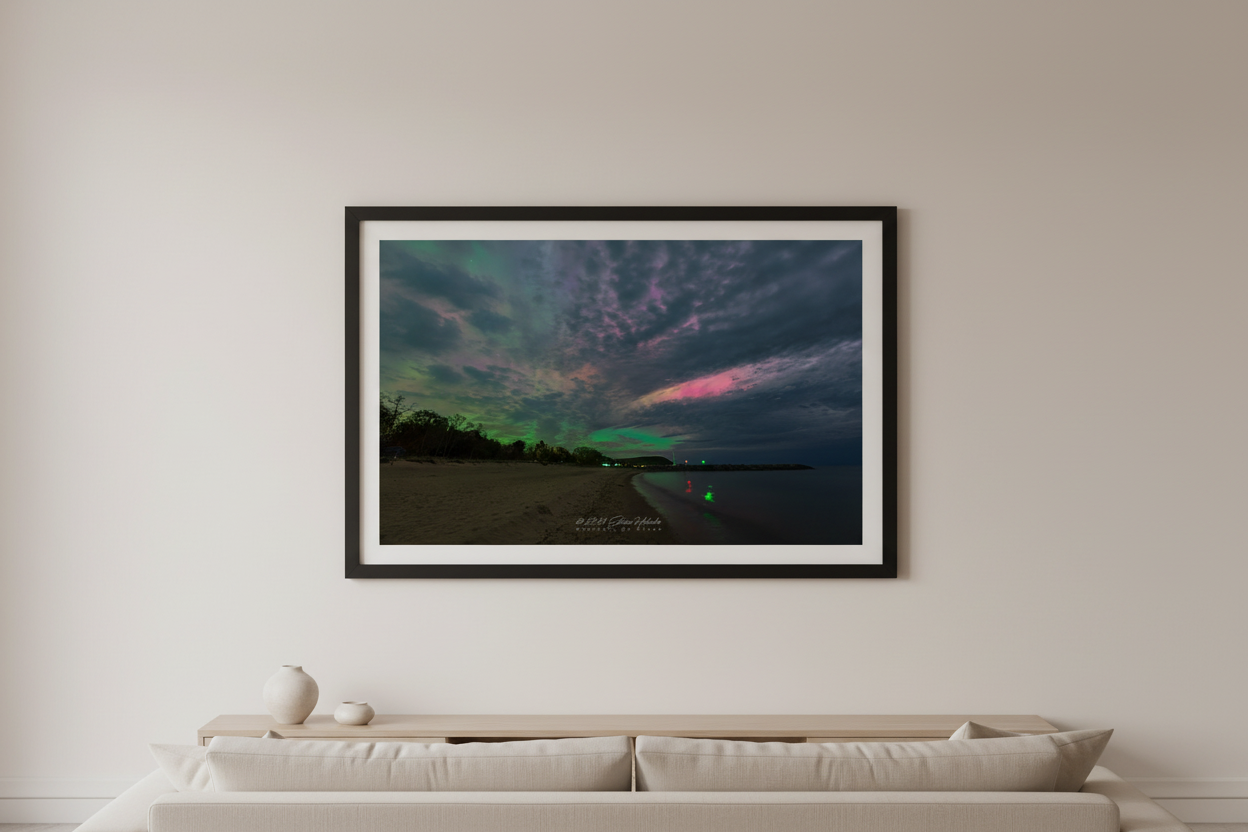 Large fine art landscape print of vivid green and pink aurora borealis illuminating dramatic clouds over Fishtown Leland Michigan beach May 10 2024 displayed in modern living room