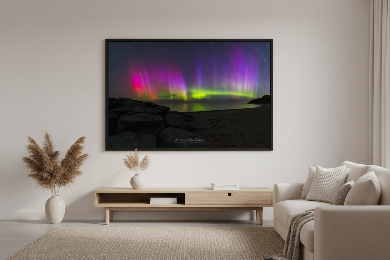 Large fine art landscape print of vivid magenta pink crimson and purple aurora borealis pillars with electric green curtains reflecting over Lake Michigan rocky shoreline at Leland Michigan May 16 2024 at 4:24am displayed in modern living room