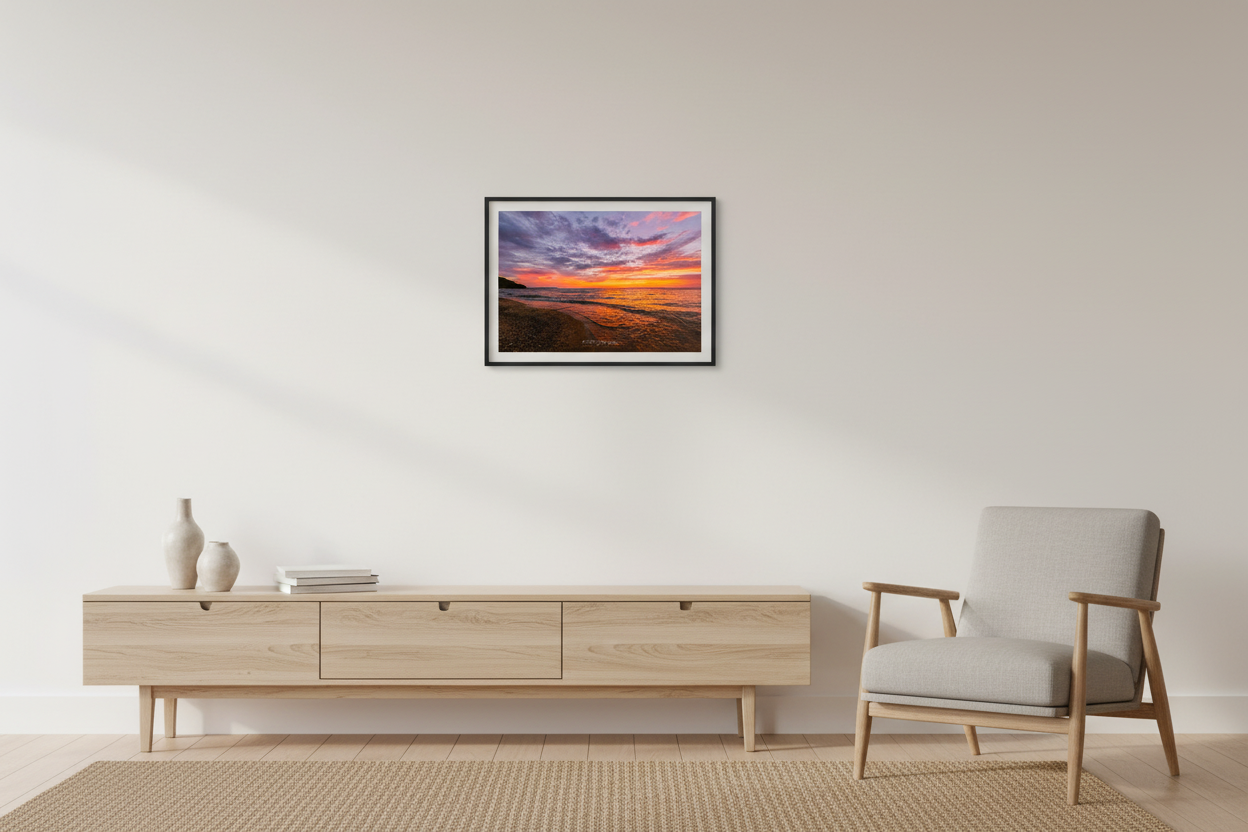 Small fine art landscape print of sweeping wide-angle purple and orange sunset sky with golden wave reflections and rocky shoreline curving toward forested headland at Leland Lake Michigan September 2023 displayed in modern living room