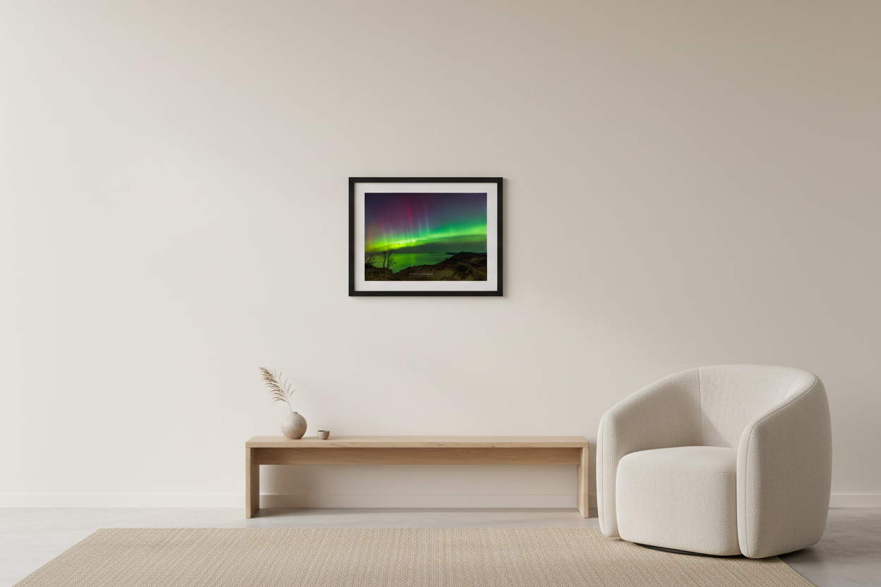Small fine art landscape print of vivid lime green yellow and crimson red aurora borealis over Lake Michigan viewed from Empire Bluffs sandy dunes with silhouetted bare trees and dune grass in foreground Sleeping Bear Dunes Michigan March 24 2023 displayed in modern living room
