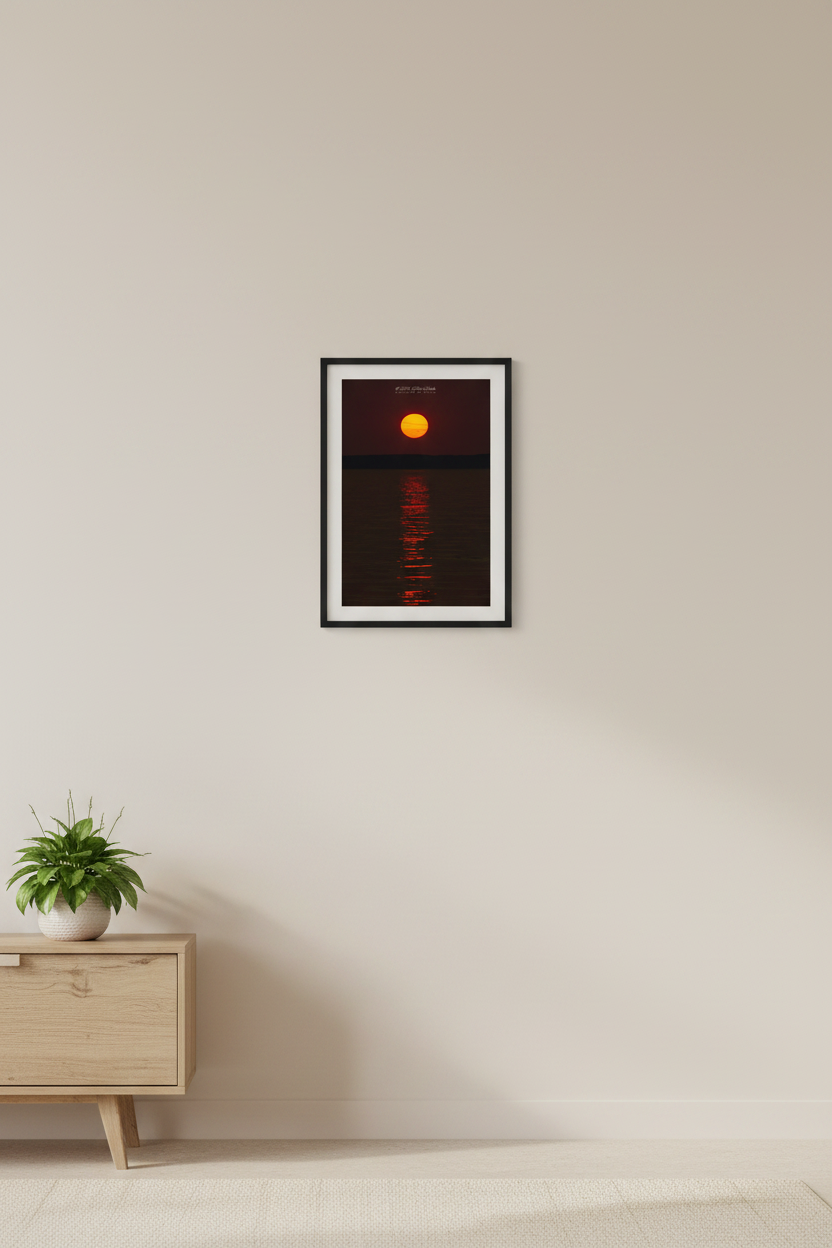 Small fine art portrait print of hazy wildfire smoke sunspot sunset over Lake Michigan with visible sunspots on solar disk and crimson rippled water reflection displayed in modern living room