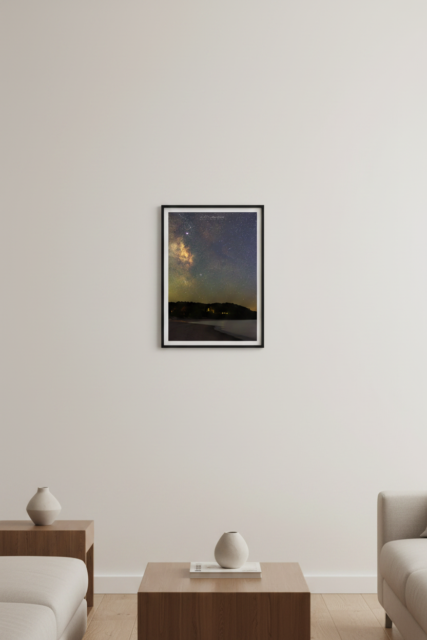 Small fine art portrait print of the Milky Way core over Leelanau Peninsula at Christmas Cove Beach Northport Michigan September 18 2023 at 9:08pm with warm amber horizon glow and silhouetted tree line across calm water displayed in modern living room