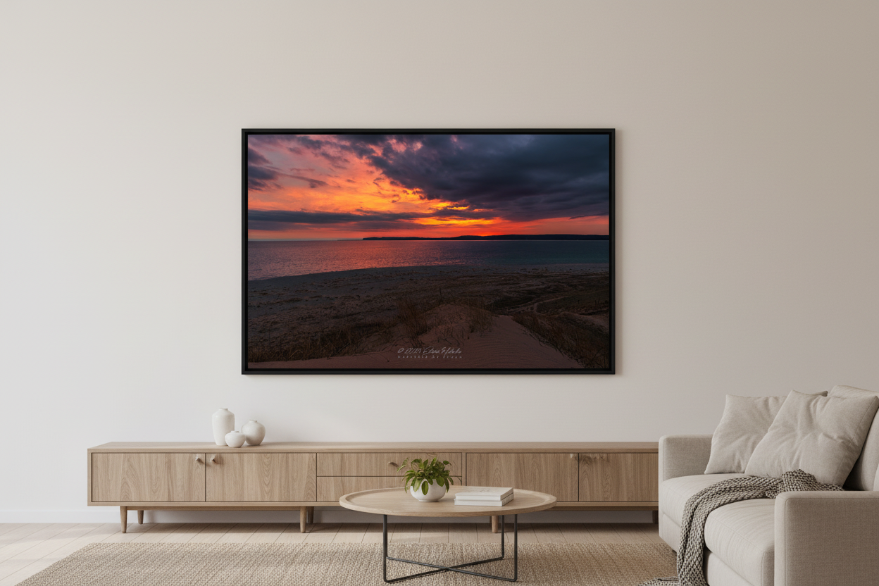 Large fine art landscape print of a dramatic fiery orange and red sunrise with stormy dark clouds over Sleeping Bear Bay from Sleeping Bear Point Michigan March 30 2024 displayed in modern living room