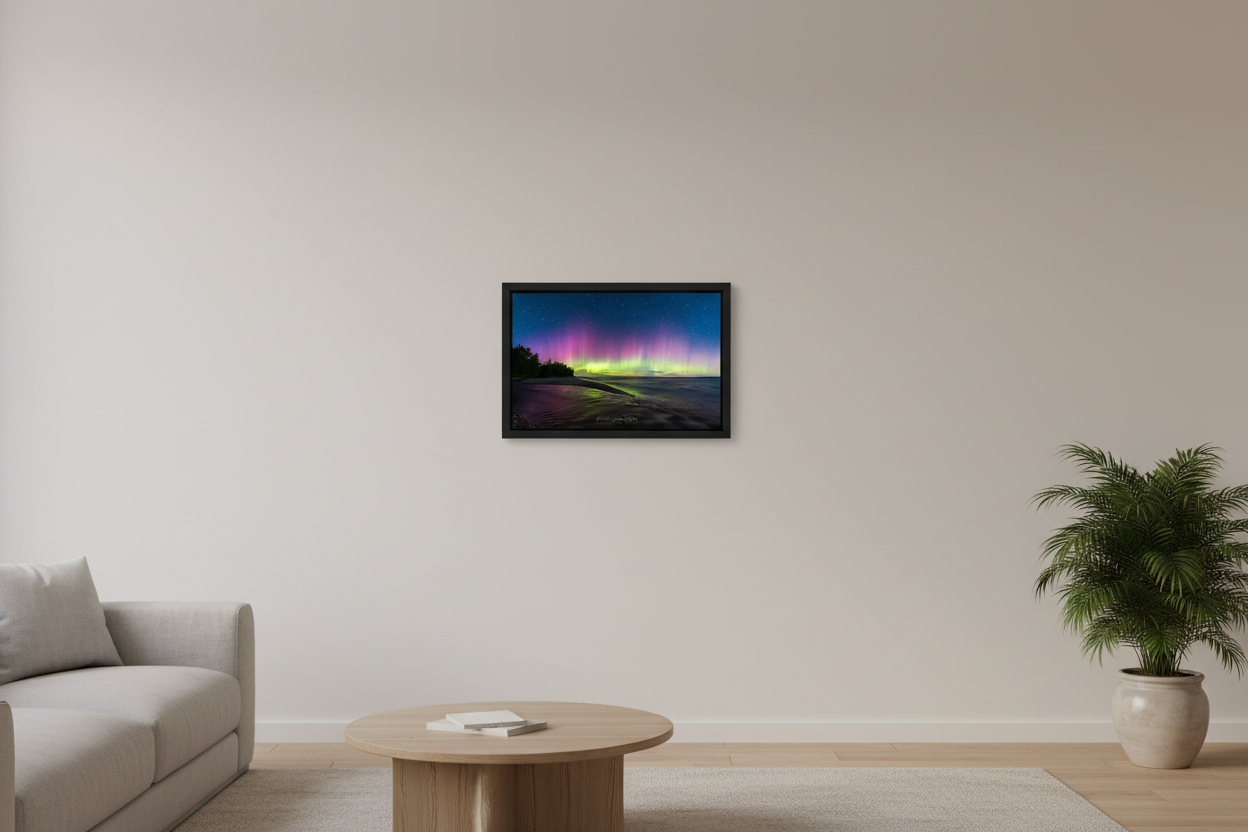 Small fine art landscape print of full-spectrum Northern Lights with vivid green base bursting into tall pink and purple pillars over Shalda Creek sandy beach shoreline with dark tree silhouettes and calm open water at Lake Michigan Michigan September 4 2022 displayed in modern living room