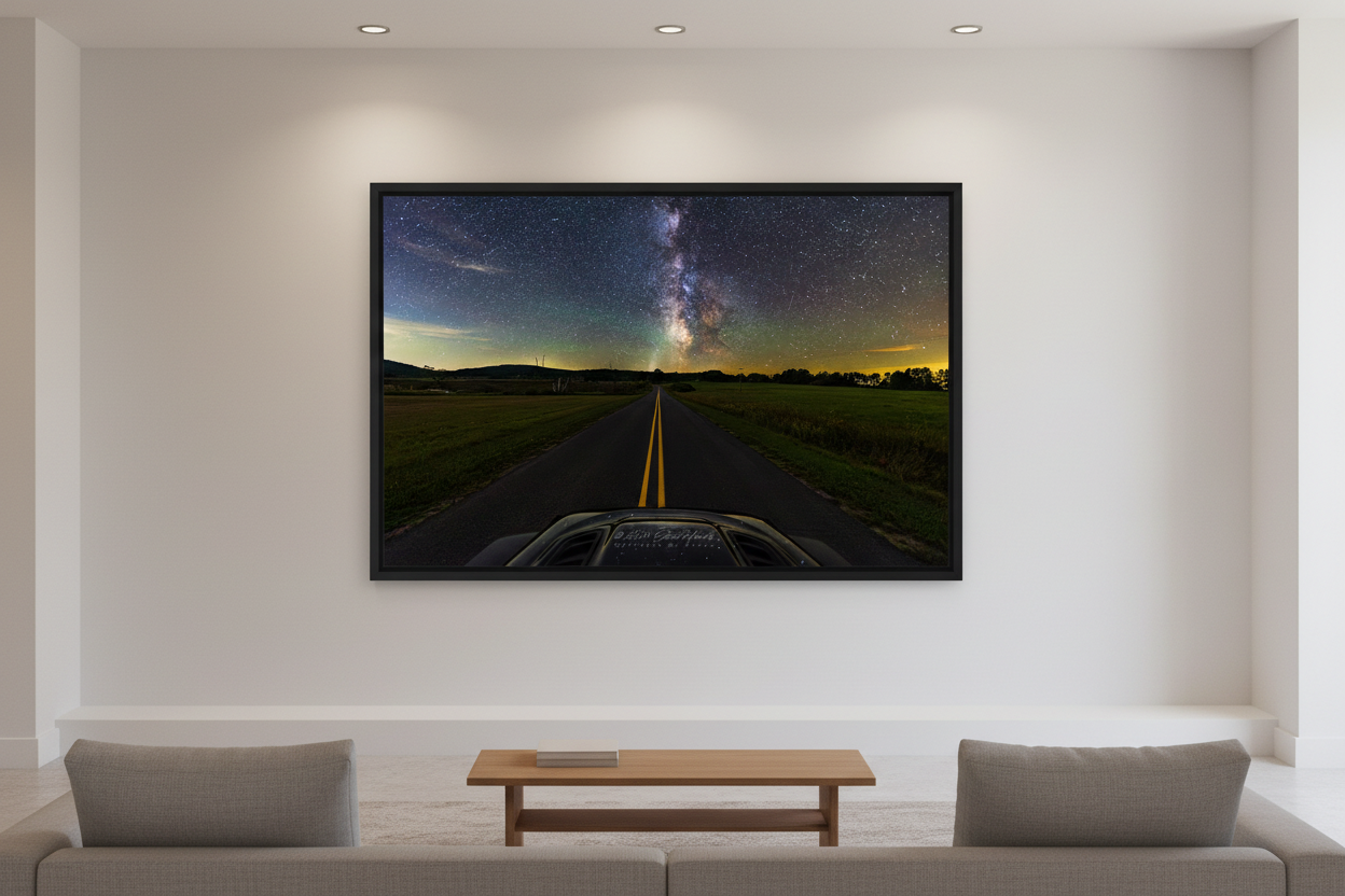 Large fine art landscape print of the Milky Way galactic core rising over a rural two-lane road viewed from vehicle hood POV with open fields and rolling hills near Sleeping Bear Dunes Michigan September 4 2024 at 10:50pm displayed in modern living room