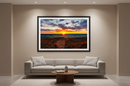 Large fine art landscape print of roped beach path leading to starburst sunset with purple orange clouds and teal waves at North Bar Beach Sleeping Bear Dunes March 2024 displayed in modern living room