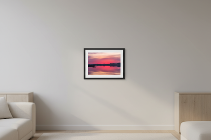 Small fine art landscape print of a vivid magenta and pink sunrise perfectly reflected in glassy calm water at Sutton's Bay with silhouetted dock and treeline Leelanau County Michigan March 12 2024 displayed in modern living room
