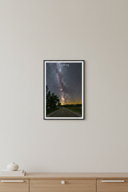 Small fine art portrait print of the Milky Way rising perfectly centered above Dune Highway road at Sleeping Bear Dunes Michigan September 8 2023 at 10:13pm with silhouetted trees and golden horizon glow displayed in modern living room