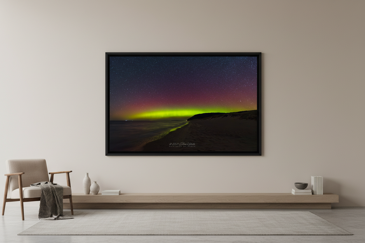 Large fine art print of crimson aurora and lime green horizon band over Lake Michigan from North Bar Lake beach with sweeping curved shoreline and forested headland bluff silhouette Sleeping Bear Dunes displayed in modern living room