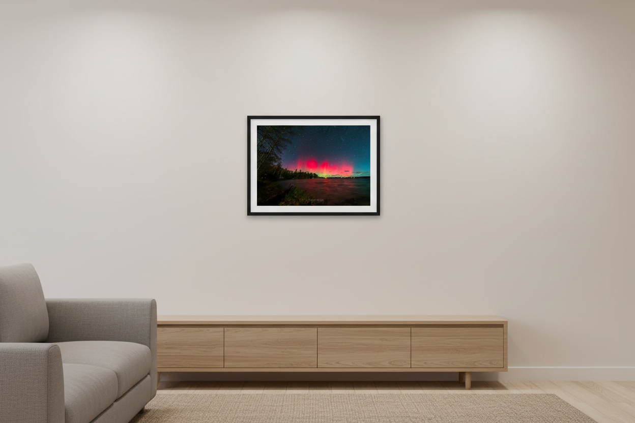 Small fine art print of single dominant crimson red aurora orb glowing over Lake Leelanau wooded shoreline from Leland Michigan November 8 2024 8:28pm with vivid water reflection displayed in modern living room