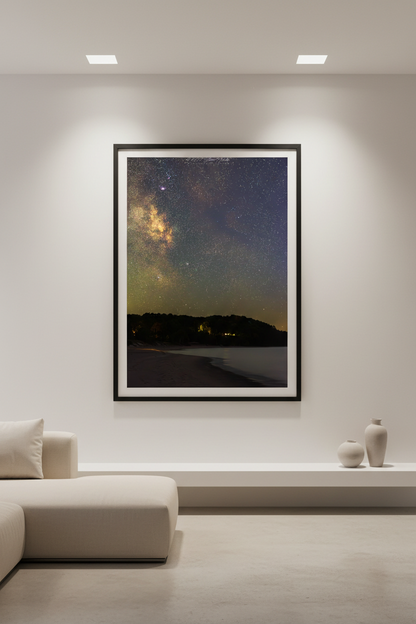 Large fine art portrait print of the Milky Way core over Leelanau Peninsula at Christmas Cove Beach Northport Michigan September 18 2023 at 9:08pm with warm amber horizon glow and silhouetted tree line across calm water displayed in modern living room