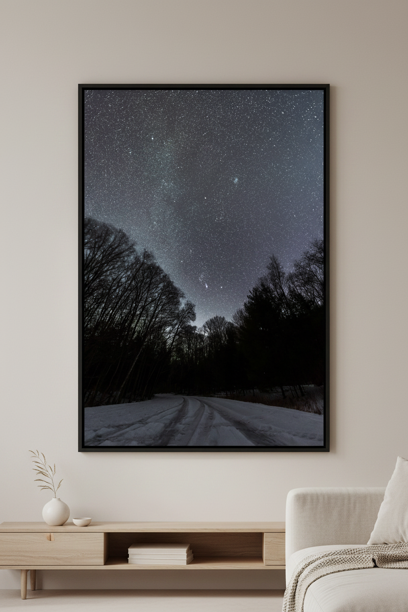 Large fine art portrait print of Comet C/2022 E3 ZTF and Orion constellation over snow-covered Pierce Stocking Drive road framed by bare winter trees at Sleeping Bear Dunes Michigan February 7 2023 displayed in modern living room