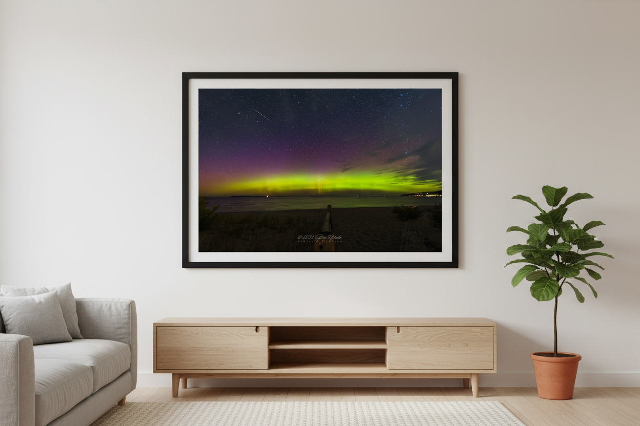 Large fine art print of wide panoramic lime green and purple Northern Lights aurora over Lake Michigan from Glen Arbor open beach with boardwalk meteor streak and distant town lights displayed in modern living room