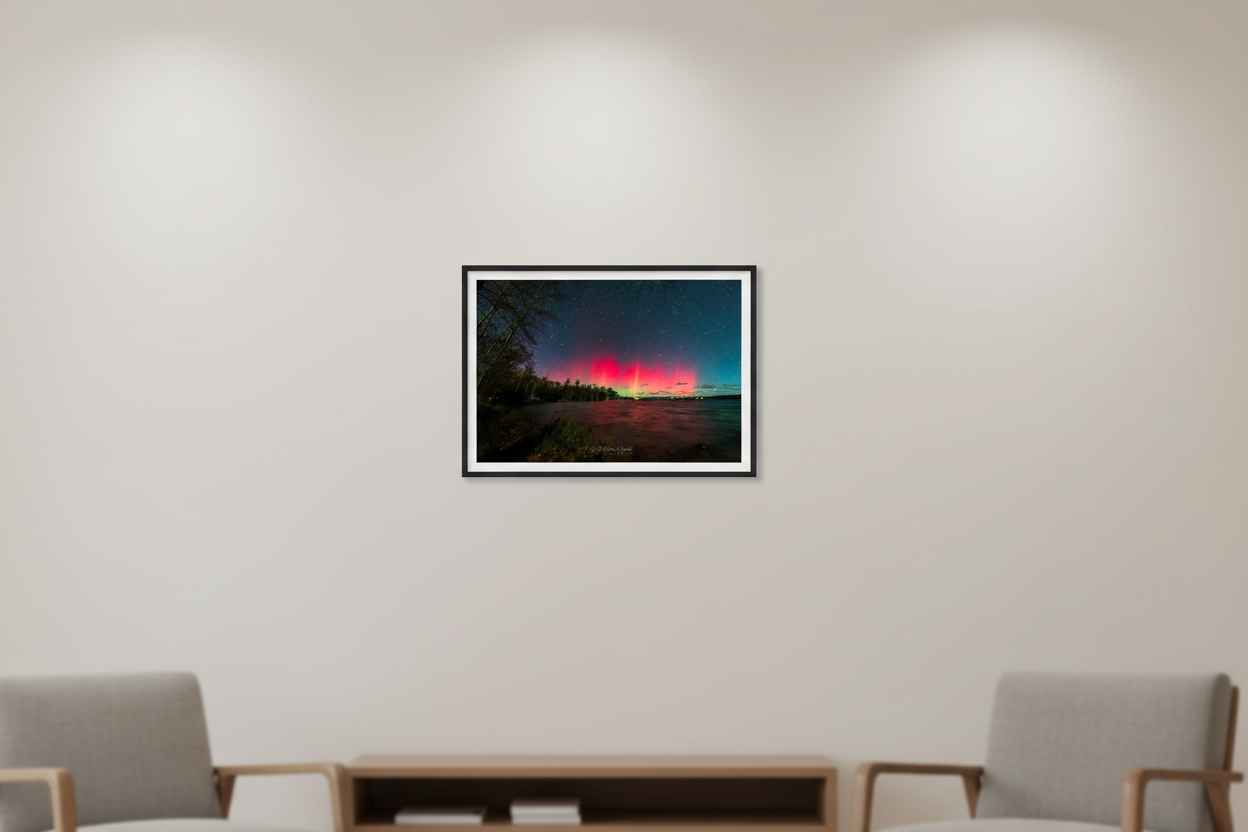 Small fine art print of double-lobe crimson red aurora arches glowing over Lake Leelanau wooded shoreline from Leland Michigan November 8 2024 8:27pm with pink water reflection and starfield displayed in modern living room