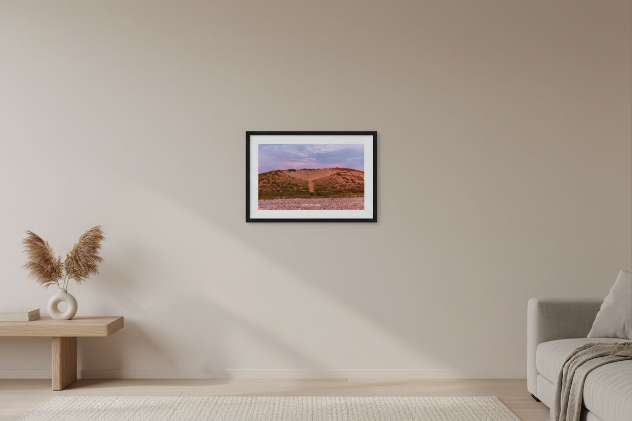 Small fine art print of warm terracotta sand dune face with rocky pebble beach foreground and soft lavender purple sky at Sleeping Bear Point MI displayed in modern living room