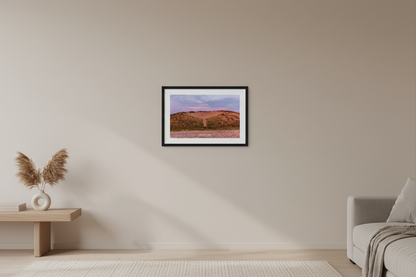 Small fine art print of warm terracotta sand dune face with rocky pebble beach foreground and soft lavender purple sky at Sleeping Bear Point MI displayed in modern living room