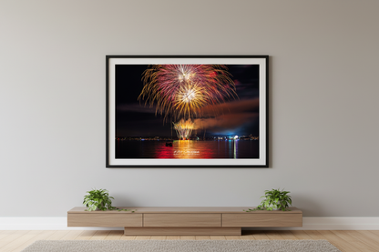Large fine art landscape print of Traverse City 4th of July 2024 fireworks showing warm gold and crimson chandelier burst with cascading willow trails and rich red-gold water reflection over Grand Traverse Bay displayed in modern living room