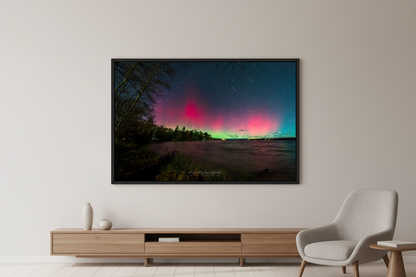 Large fine art print of split dual aurora structures with crimson left column and soft pink right glow over Lake Leelanau from Leland Michigan November 8 2024 8:33pm with meteor streak and water reflection displayed in modern living room