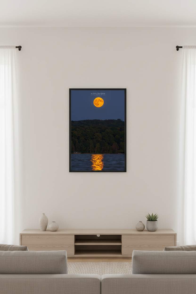 Small fine art portrait print of golden orange full harvest supermoon rising over Lake Leelanau with shimmering moonpath reflection on rippled water and dark deciduous hillside silhouette deep blue twilight sky Leland Michigan displayed in modern living room