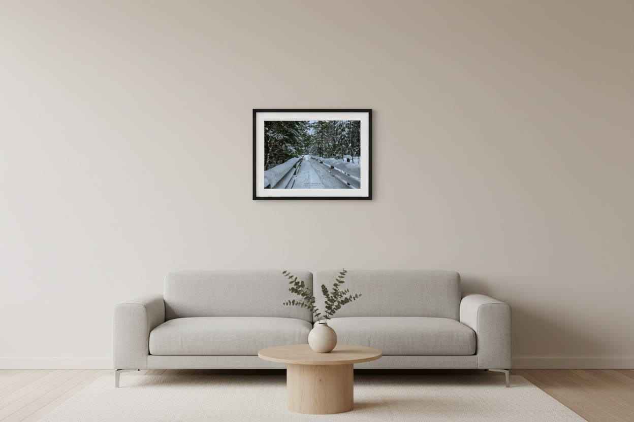 Small fine art landscape print of snow-covered boardwalk with split-rail fencing leading into snow-laden evergreen forest in Michigan Upper Peninsula February 5 2023 displayed in modern living room
