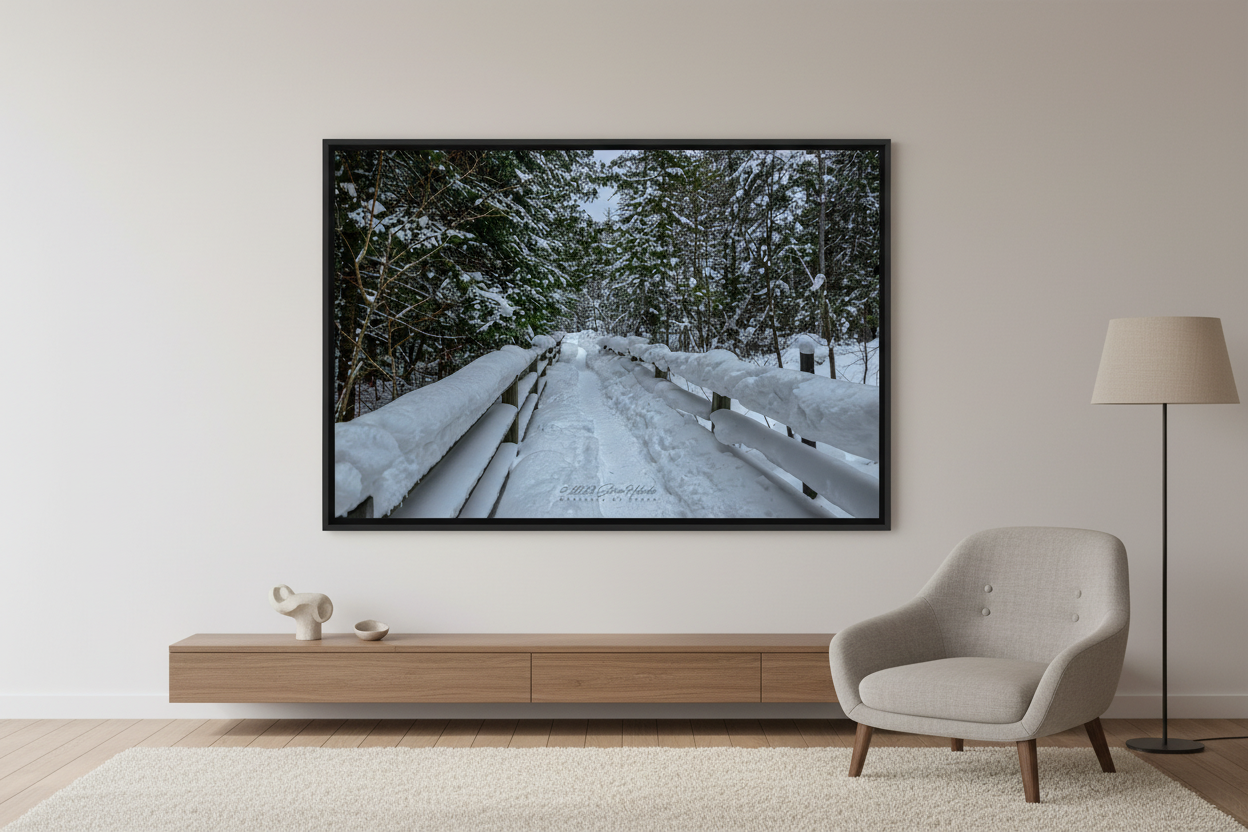 Large fine art landscape print of snow-covered boardwalk with split-rail fencing leading into snow-laden evergreen forest in Michigan Upper Peninsula February 5 2023 displayed in modern living room