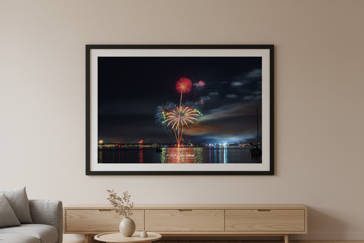 Large fine art landscape print of Traverse City 4th of July 2024 fireworks showing a red chrysanthemum atop a tall rocket trail with a wide golden palm burst below over Grand Traverse Bay with moody cloud-swept sky displayed in modern living room
