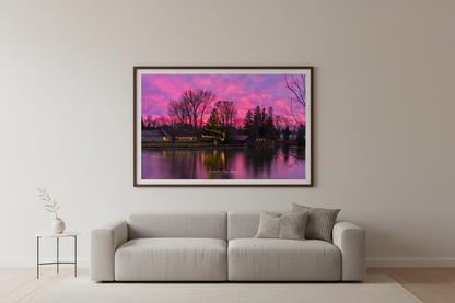 Large fine art landscape print of Christmas sunset over Leland River with lit tree and pink sky displayed in modern living room