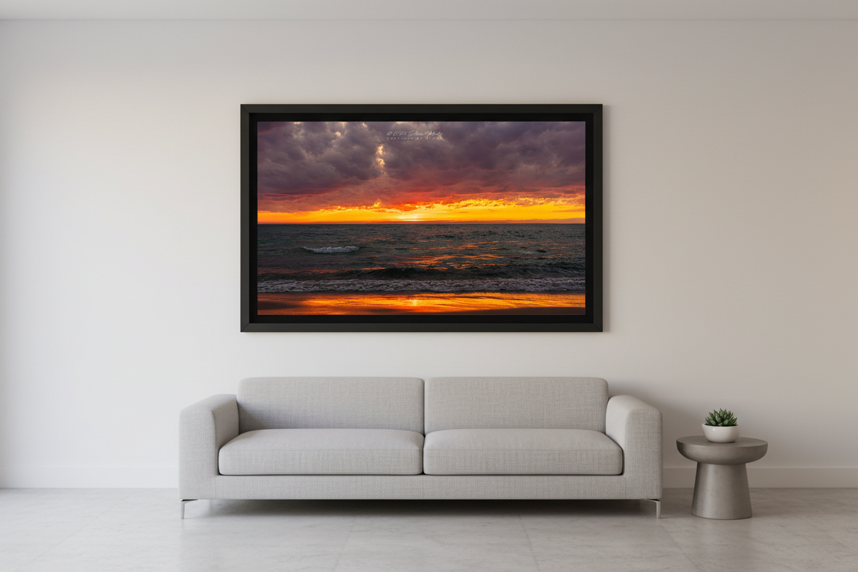 Large fine art landscape print of a dramatic fiery orange and crimson sunset afterglow with storm clouds over Lake Michigan from Port Oneida Michigan April 27 2024 displayed in modern living room