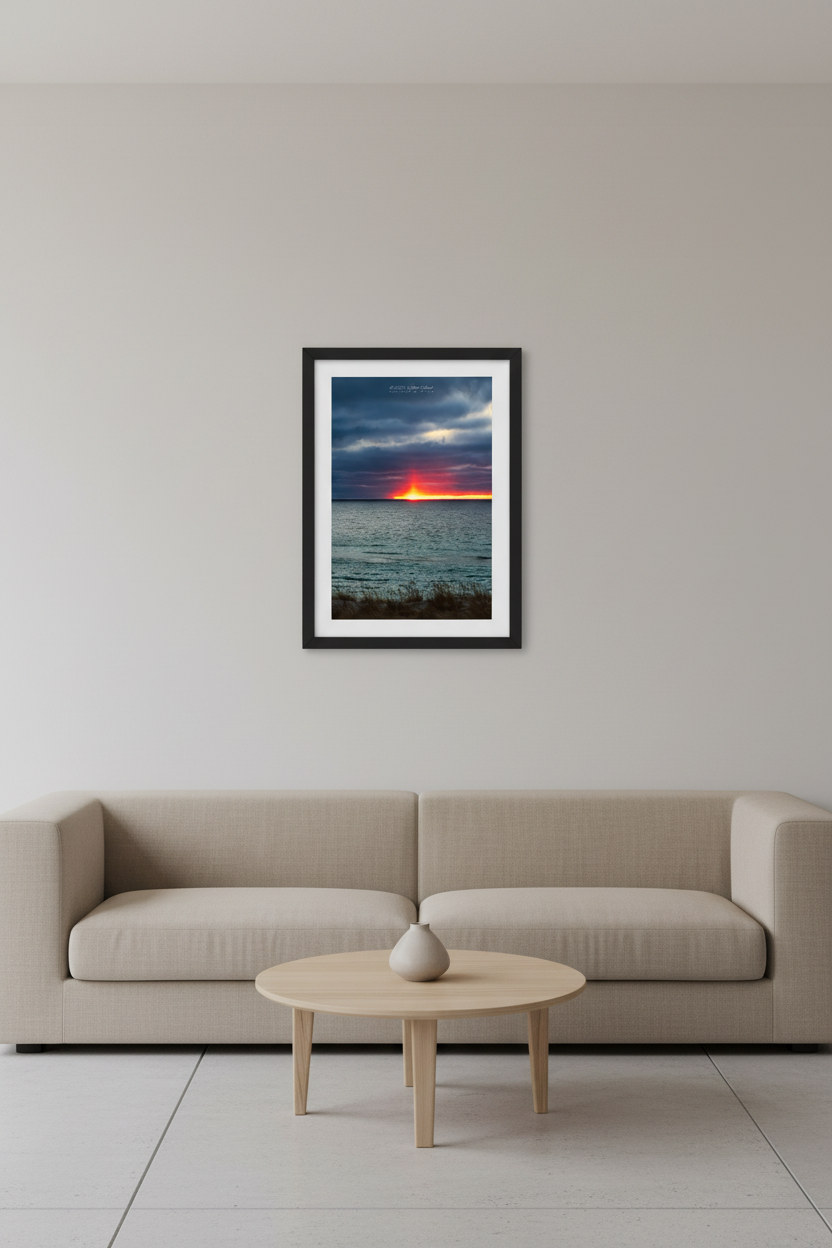 Small fine art portrait print of a rare sun pillar phenomenon at sunset over Lake Michigan from North Bar Lake with fiery red-orange light column rising above the horizon and moody storm clouds February 23 2024 displayed in modern living room