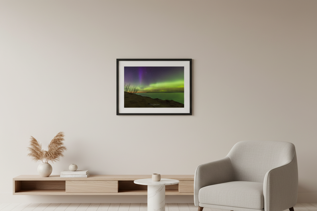 Small fine art landscape print of vivid green aurora band and purple violet pillars over Lake Michigan from Sleeping Bear Dunes overlook with sandy dunes and silhouetted trees March 23 2023 displayed in modern living room