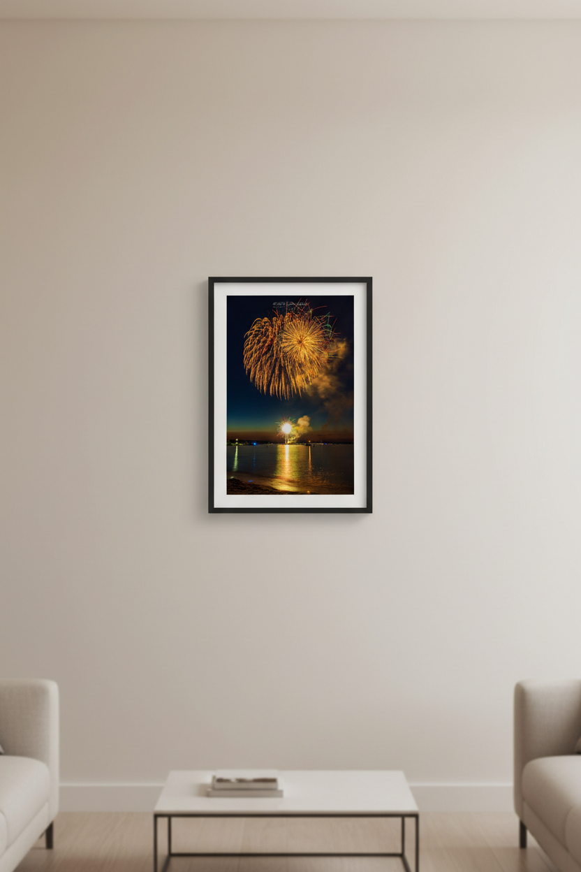 Small fine art portrait print of Traverse City Cherry Festival 2024 finale fireworks featuring two simultaneous bursts at different heights with massive golden chrysanthemum dome and small horizon starburst over Grand Traverse Bay from Clinch Park Beach displayed in modern living room
