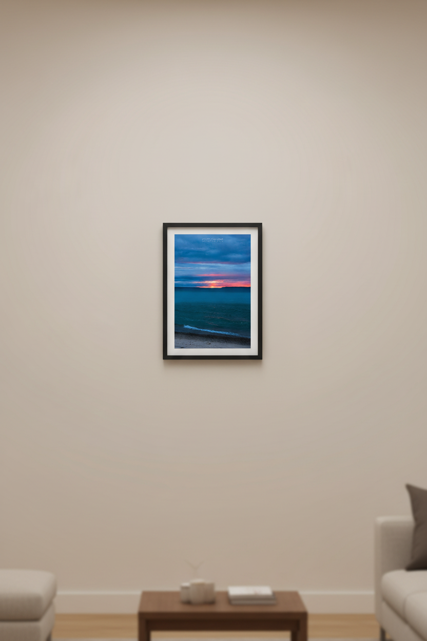Small fine art portrait print of a moody long exposure sunset afterglow with fiery orange horizon splitting the Manitou Islands over teal blue Lake Michigan from Leland Michigan April 4 2024 displayed in modern living room