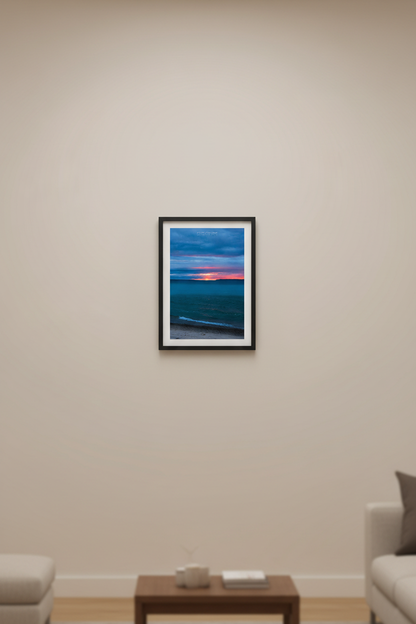 Small fine art portrait print of a moody long exposure sunset afterglow with fiery orange horizon splitting the Manitou Islands over teal blue Lake Michigan from Leland Michigan April 4 2024 displayed in modern living room