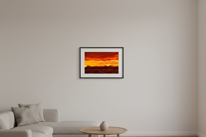 Small fine art landscape print of silhouetted crashing waves backlit by deep crimson and molten gold sunset sky at Leland Lake Michigan October 2023 displayed in modern living room