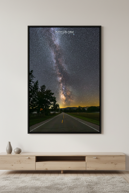Large fine art portrait print of the Milky Way rising perfectly centered above Dune Highway road at Sleeping Bear Dunes Michigan September 8 2023 at 10:13pm with silhouetted trees and golden horizon glow displayed in modern living room