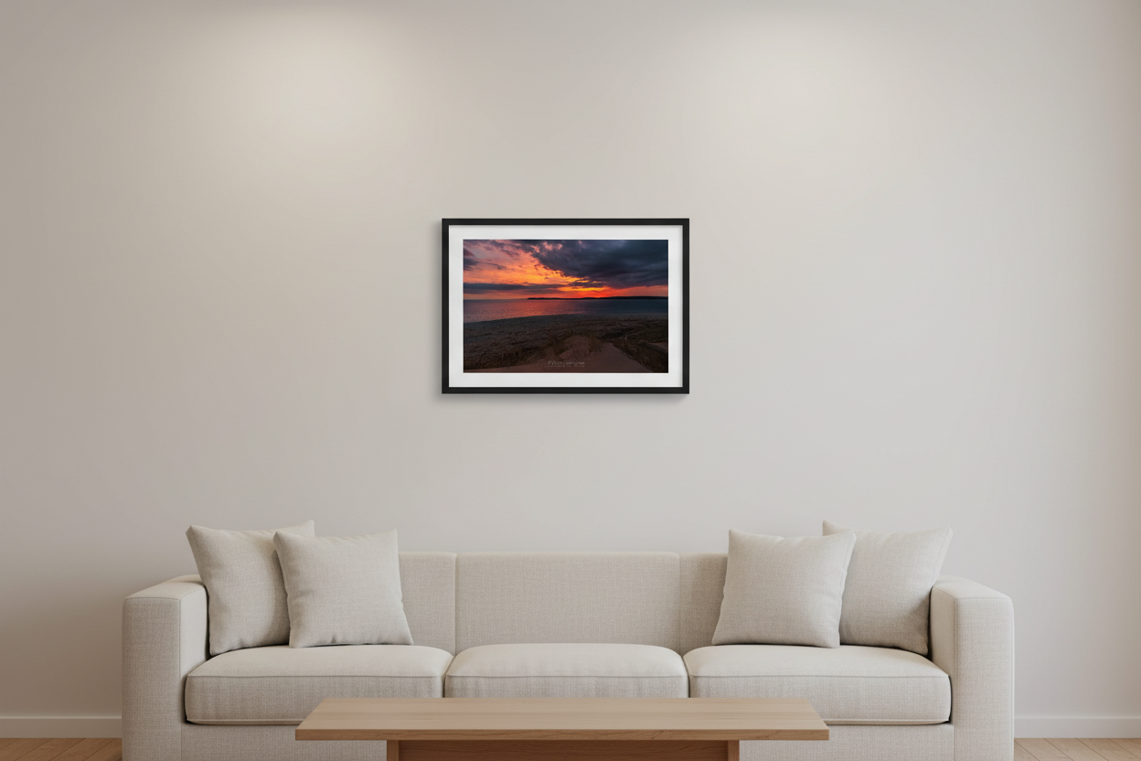Small fine art landscape print of a dramatic fiery orange and red sunrise with stormy dark clouds over Sleeping Bear Bay from Sleeping Bear Point Michigan March 30 2024 displayed in modern living room